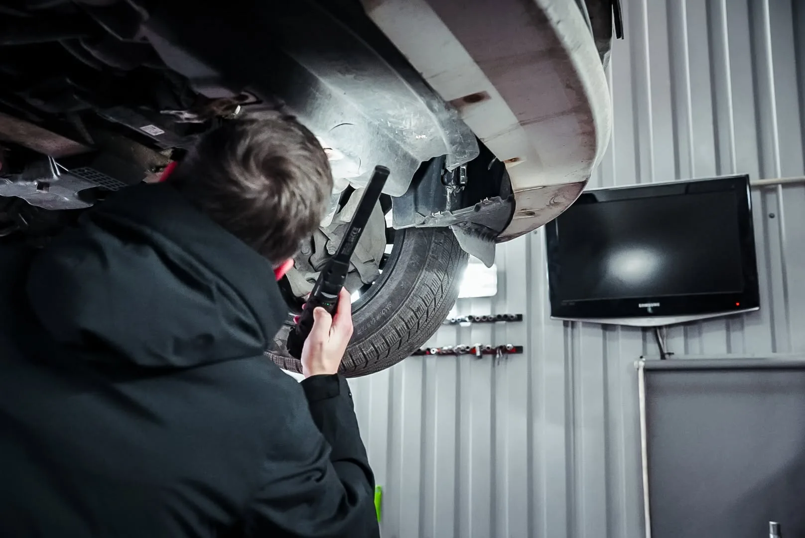 Autobrothers dirbtuvės — automobilis ant keltuvo prie įrankių sienos